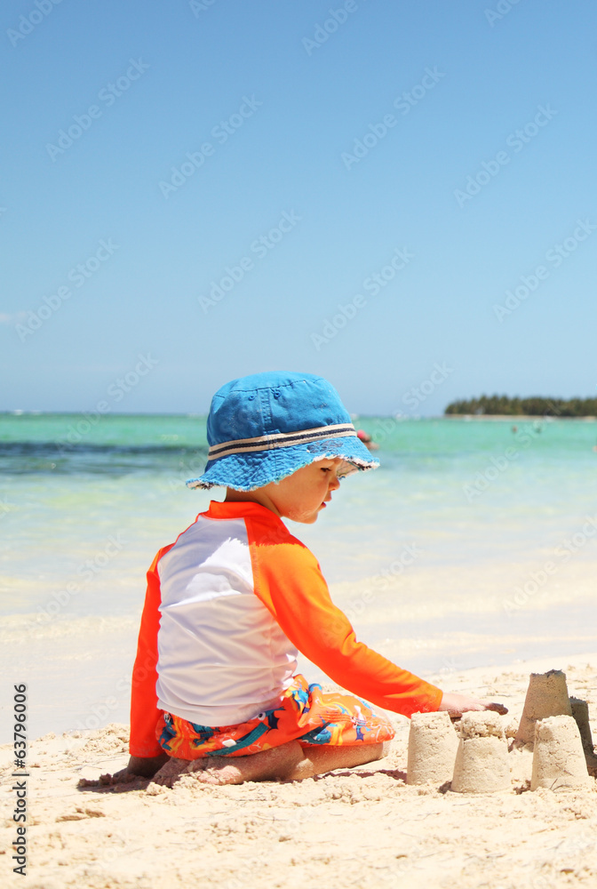 One caucasian boy playing with sand at tropical beach One caucasian boy playing with sand at tropical beach