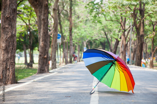 Multicolored umbrella resting on the pavement.