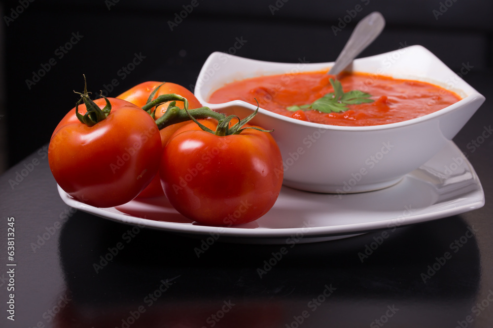 tomato soup with fresh tomatoes on black background tomato soup with fresh tomatoes on black background