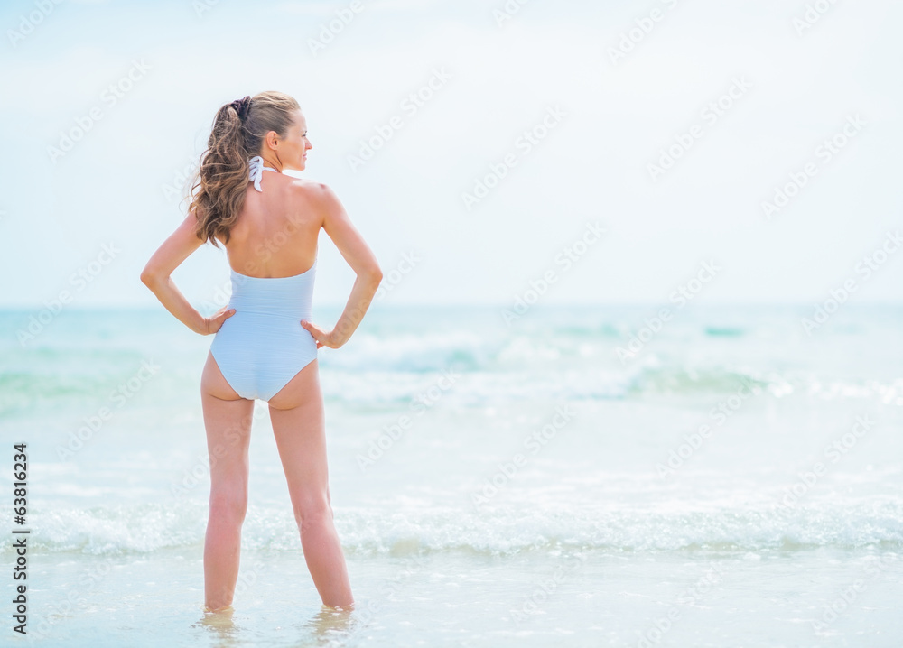 Fototapeta premium Full length portrait of young woman in swimsuit standing in sea