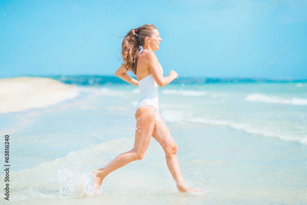 Happy young woman in swimsuit running into sea Happy young woman in swimsuit running into sea