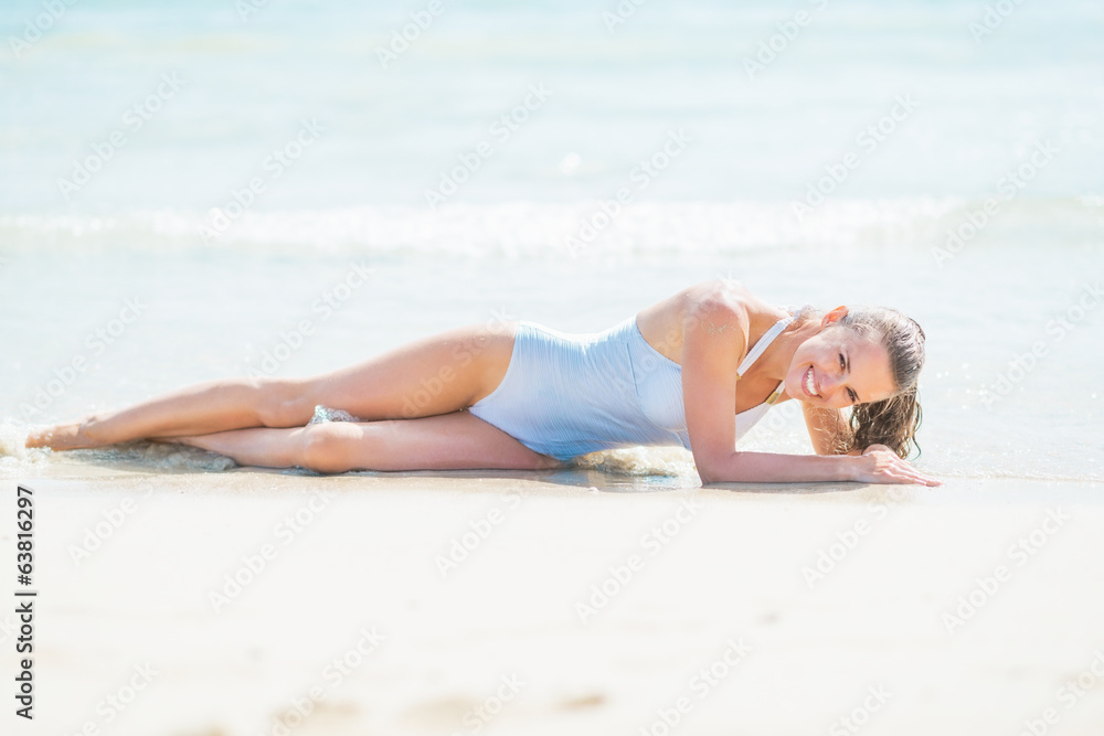 Happy young woman in swimsuit laying on sea shore Happy young woman in swimsuit laying on sea shore