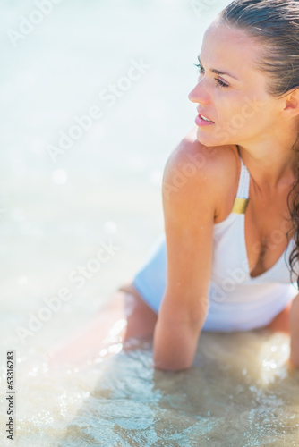 Young woman in swimsuit sitting at seaside