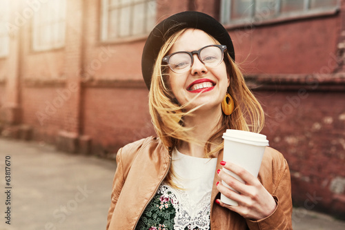 Cheerful woman in the street drinking morning coffee in sunshine