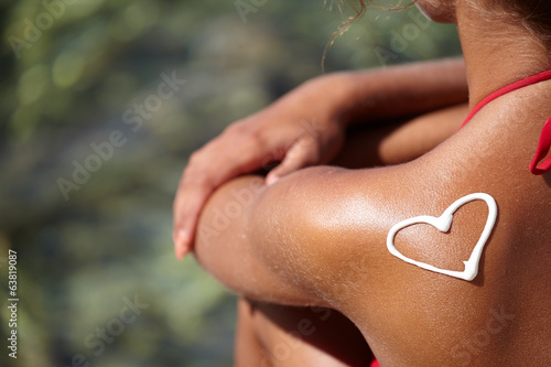 teenage girls back with sunburn and heart of sun lotion photo
