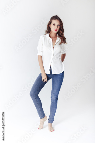 Fashion model in a blouse and jeans barefoot on a white backgrou