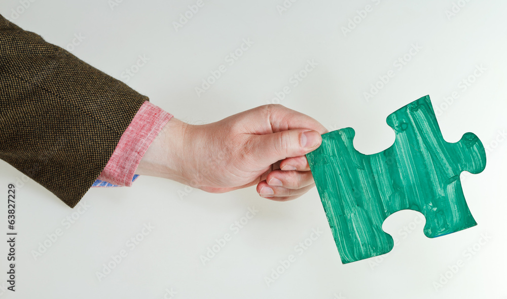 green painted puzzle piece in male hand green painted puzzle piece in male hand