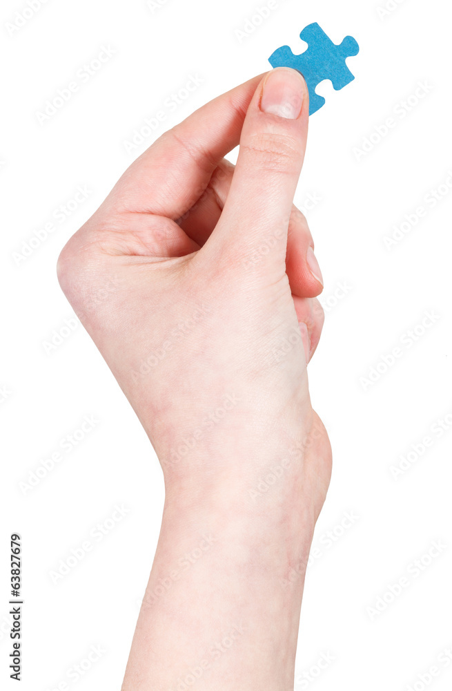 female hand holding jigsaw puzzle piece female hand holding jigsaw puzzle piece