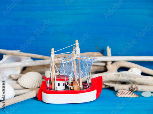 Toy sailboat, weathered wood and seashells on blue wood