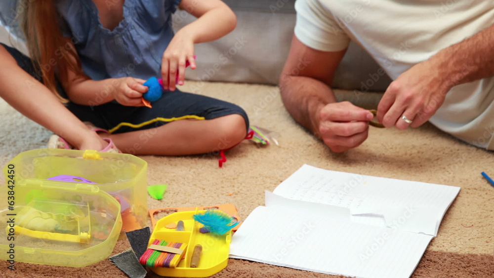 Young siblings doing arts and crafts on the rug with parents Young siblings doing arts and crafts on the rug with parents