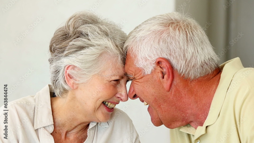 Senior couple sitting at the table touching heads Senior couple sitting at the table touching heads