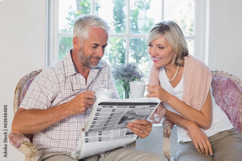 Couple reading newspaper while drinking coffee Couple reading newspaper while drinking coffee