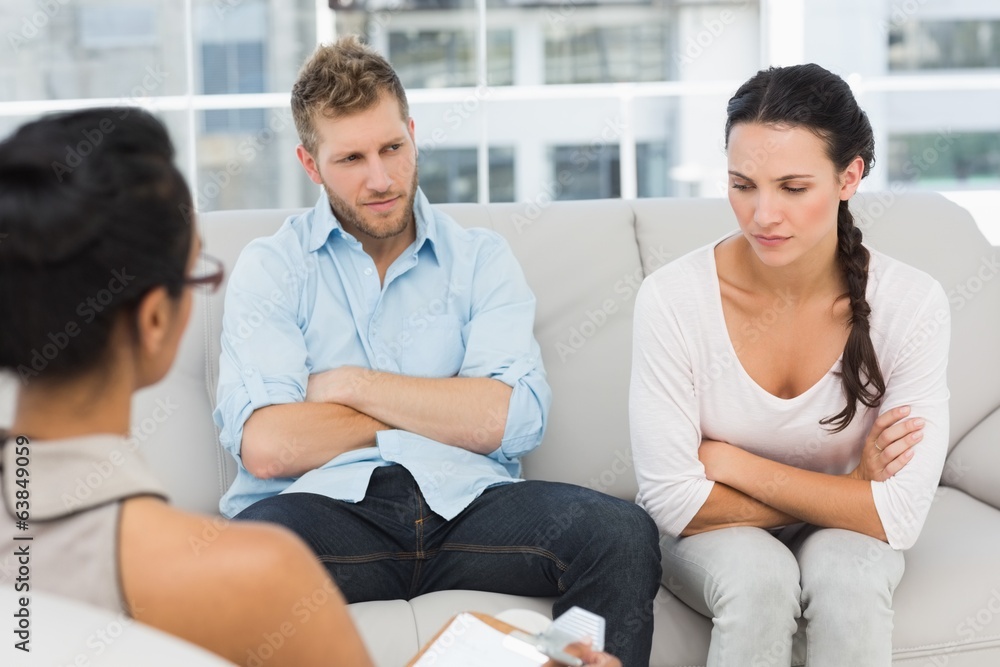 Unhappy couple with arms crossed at therapy session Unhappy couple with arms crossed at therapy session