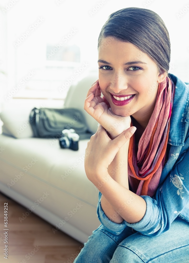 Fototapeta premium Young brunette sitting on sofa looking at camera