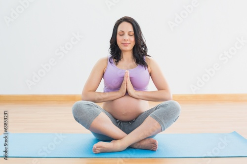 Pregnant woman sitting on mat in lotus pose