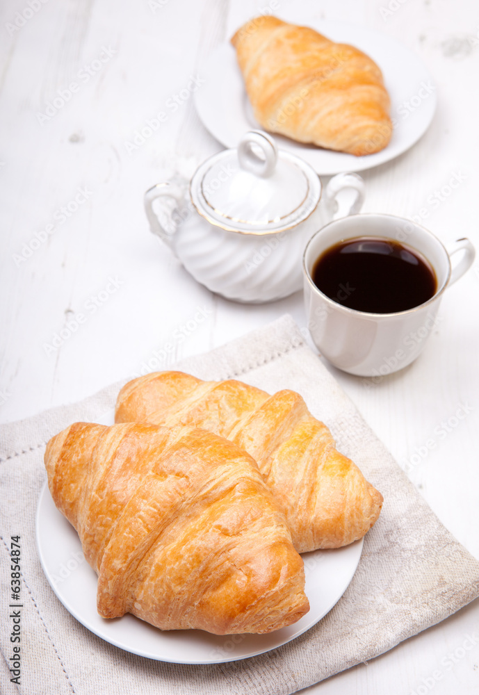 Two croissants with coffee on the white table