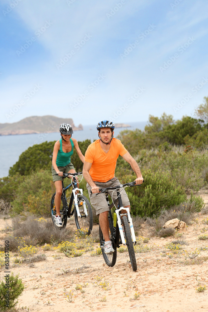 Couple riding bikes on island trail Couple riding bikes on island trail