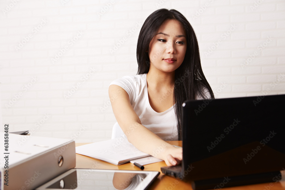 Studentin am Schreibtisch, tippt auf der Computertastatur Studentin am Schreibtisch, tippt auf der Computertastatur