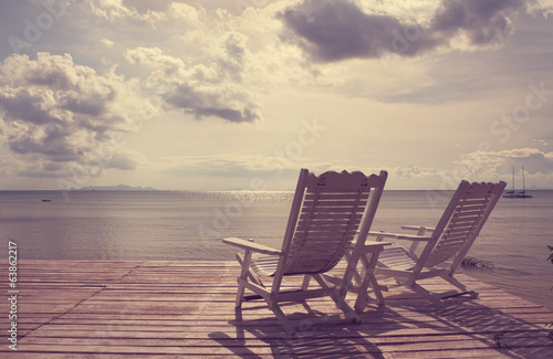 White wooden beach chair facing seascape vintage filter effect