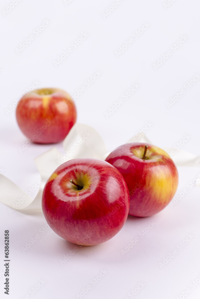 Three red apples on white background and ribbon Three red apples on white background and ribbon