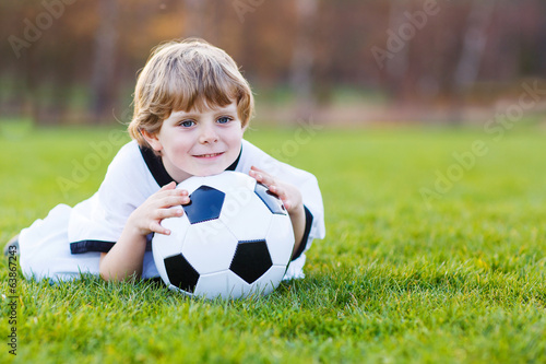 Blond boy of 4 playing soccer with football on football field © Irina Schmidt