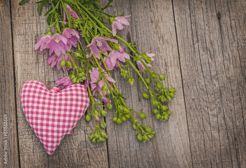Rustic still life with a bouquet of pink flowers and heart photo