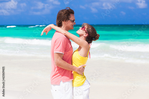 half face view of romantic couple hugging on tropical beach