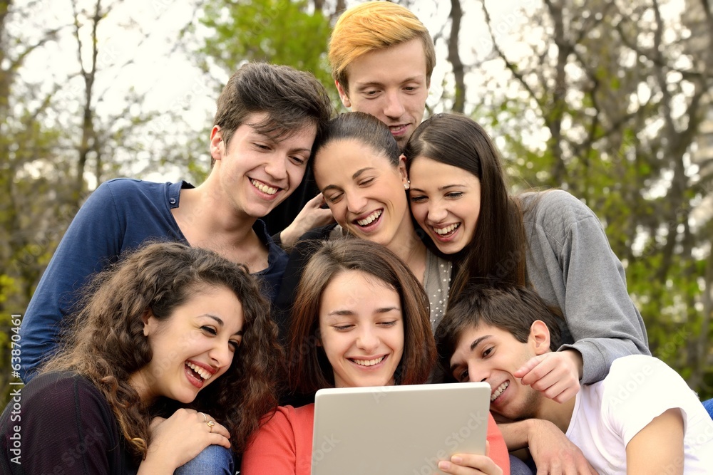 Group of young adults browsing a tablet outside Group of young adults browsing a tablet outside
