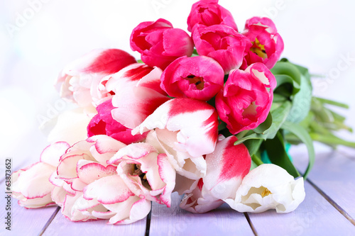 Beautiful tulips on color wooden table  on light background