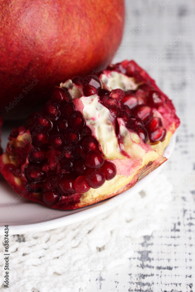Ripe pomegranates on plate, on color wooden background Ripe pomegranates on plate, on color wooden background