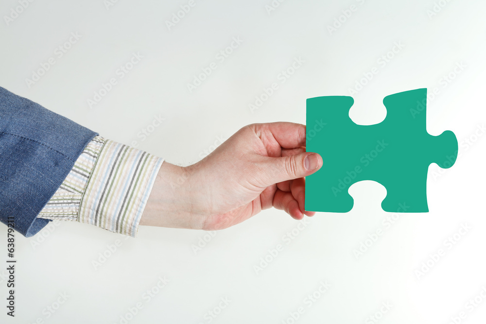 male hand holding green puzzle piece male hand holding green puzzle piece