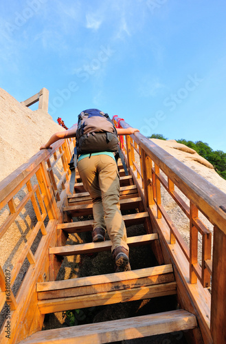  woman hiker climbing wooden stairs to peak of mountain huashan