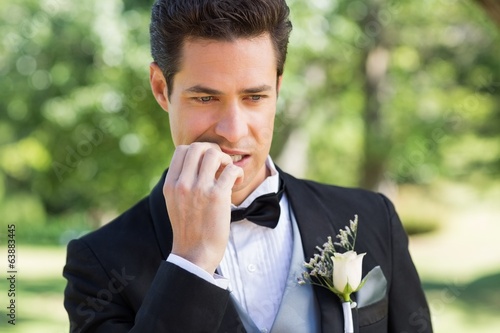 Groom biting nails in garden photo