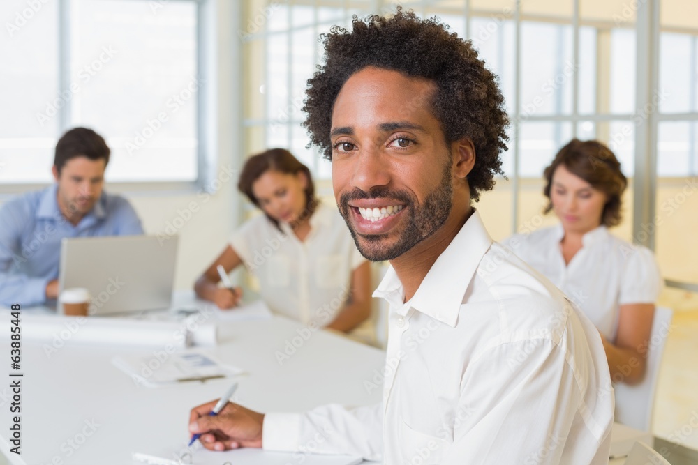 Smiling businessman with colleagues in meeting at office Smiling businessman with colleagues in meeting at office