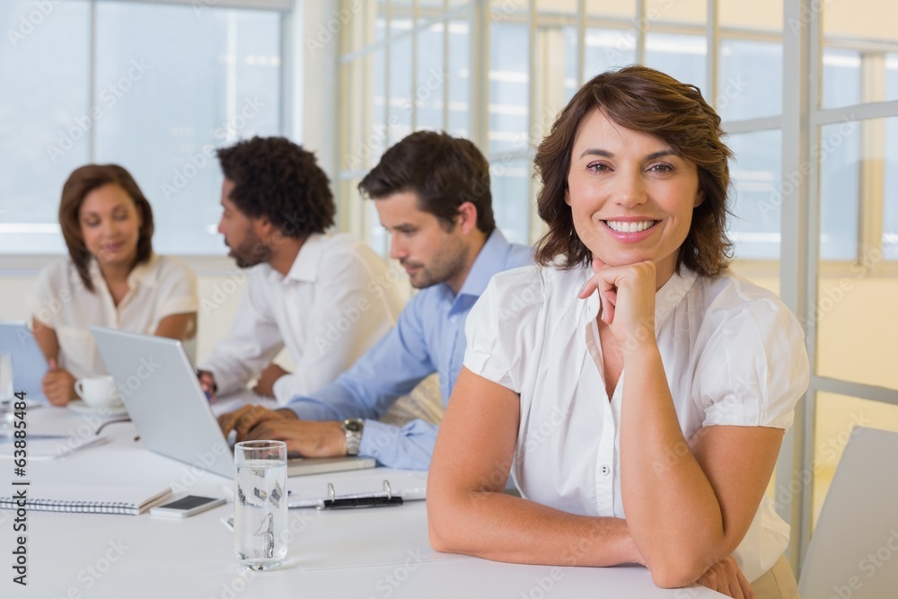 Smiling businesswoman with colleagues in meeting at office Smiling businesswoman with colleagues in meeting at office