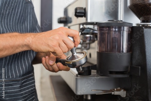Mid section of a barista prepares espresso in coffees hop