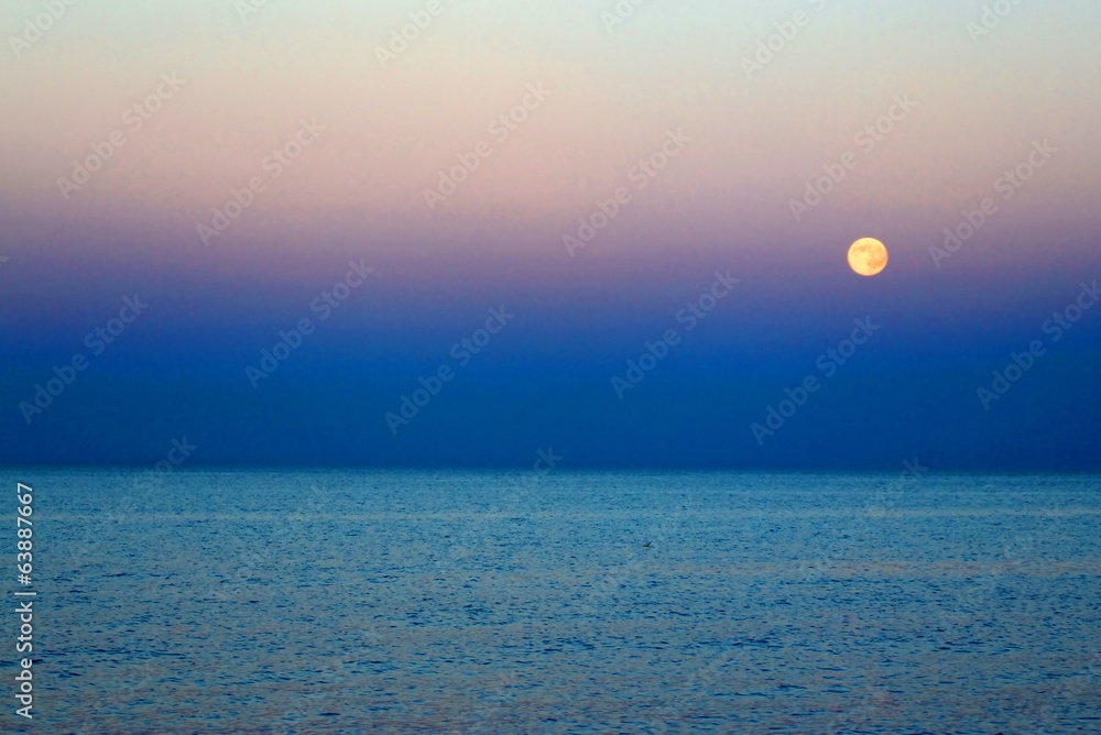 Moon that rises above the blue sea at nightfall