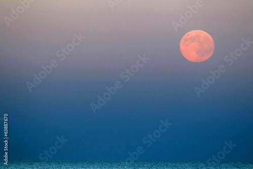 Moon that rises above the blue sea