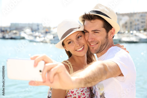 happy couple of tourists taking pictures with smartphone © goodluz