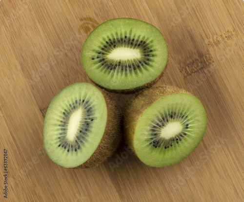 Top view of three sliced juicy kiwi fruit on wooden floor