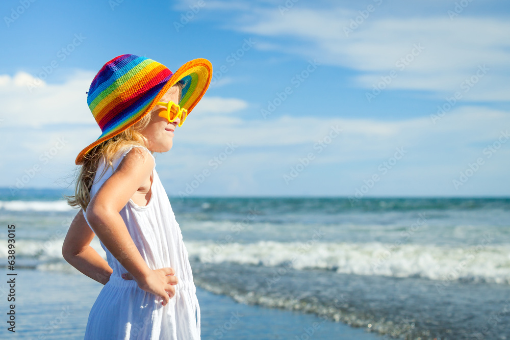 happy little girl in the hat  standing at the beach in the day t