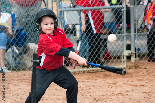 Photography Young baseball player hitting ball off a tee during game