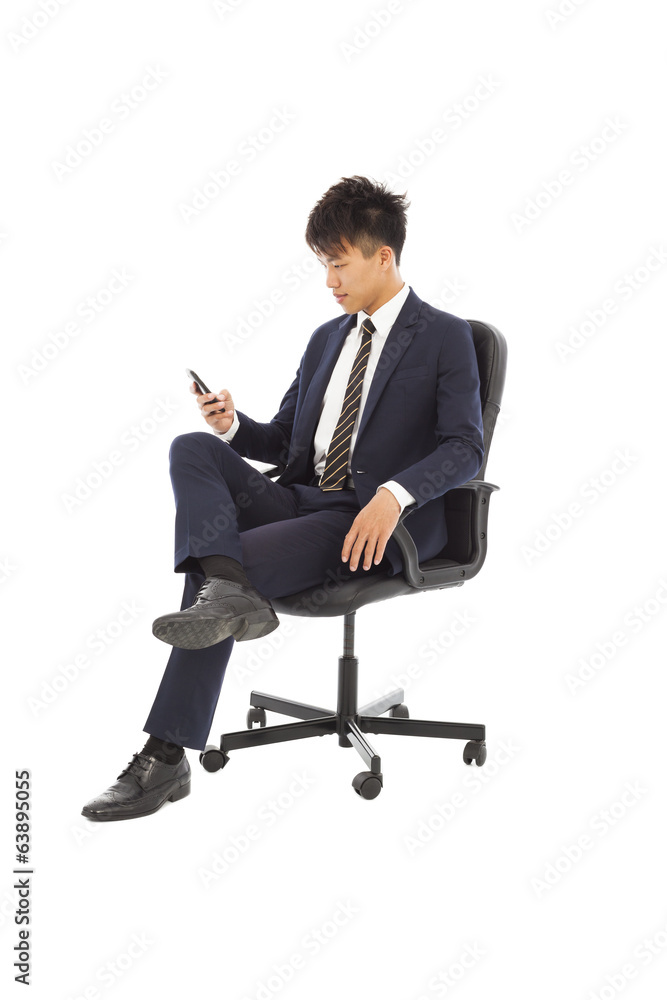 Young businessman sitting in a chair and watching smartphone Young businessman sitting in a chair and watching smartphone