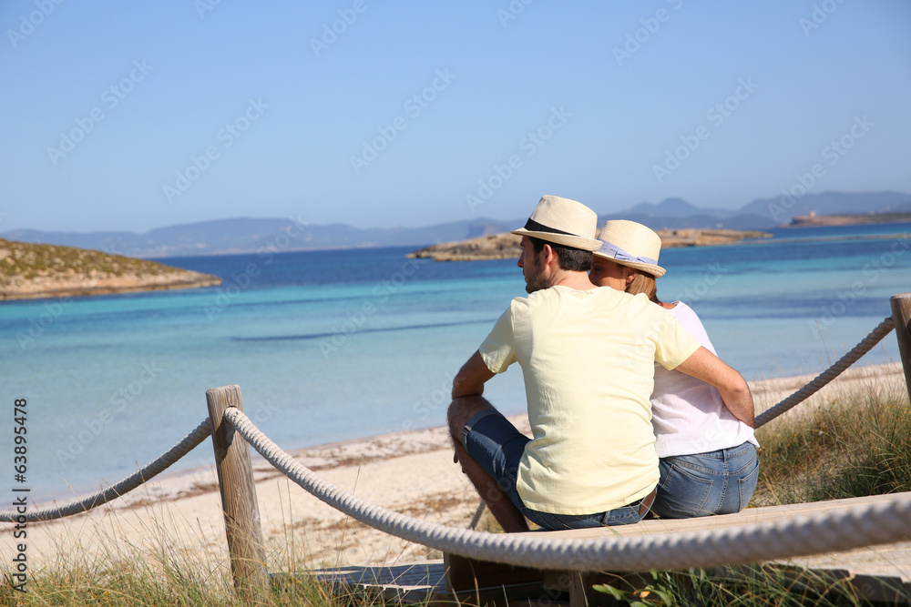 Back view of couple relaxing on beach pontoon