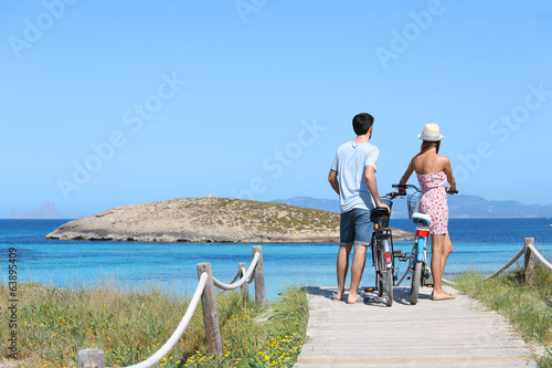 Foto Couple standing by gorgeous beach with bicycles