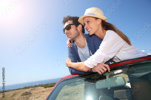 Couple enjoying view from top of convertible car