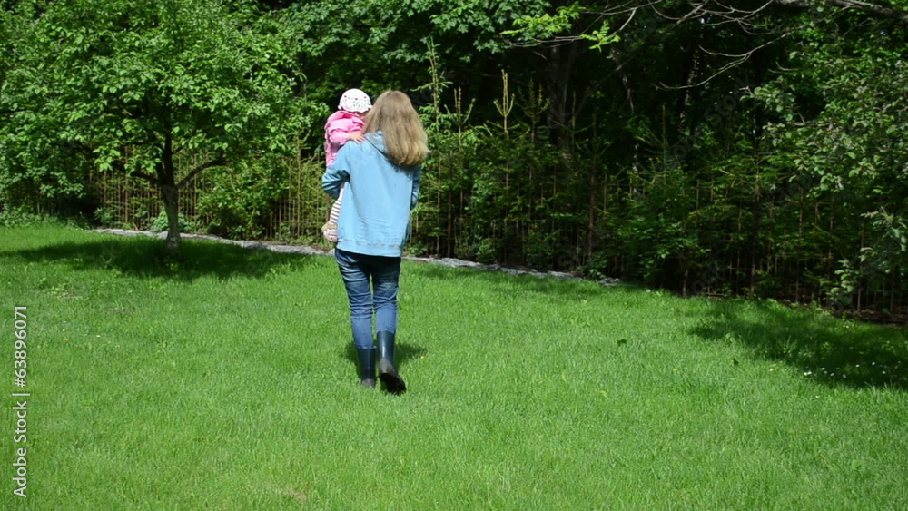 nanny have fun with little girl in garden takes child on hand nanny have fun with little girl in garden takes child on hand