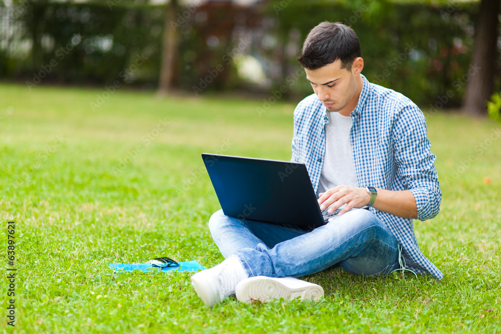 Student using a laptop on the grass Student using a laptop on the grass