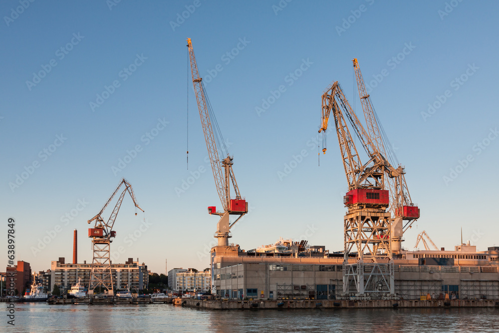 sea port cranes with blue cloudy sky in background and water in