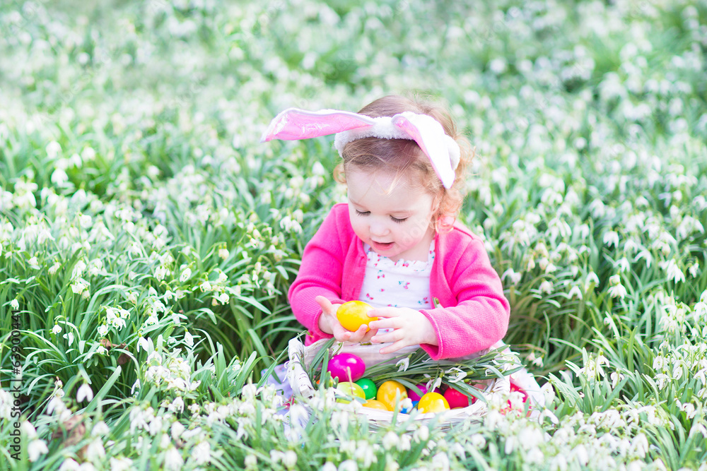 Little toddler girl wearing bunny ears playing with Easter eggs Little toddler girl wearing bunny ears playing with Easter eggs
